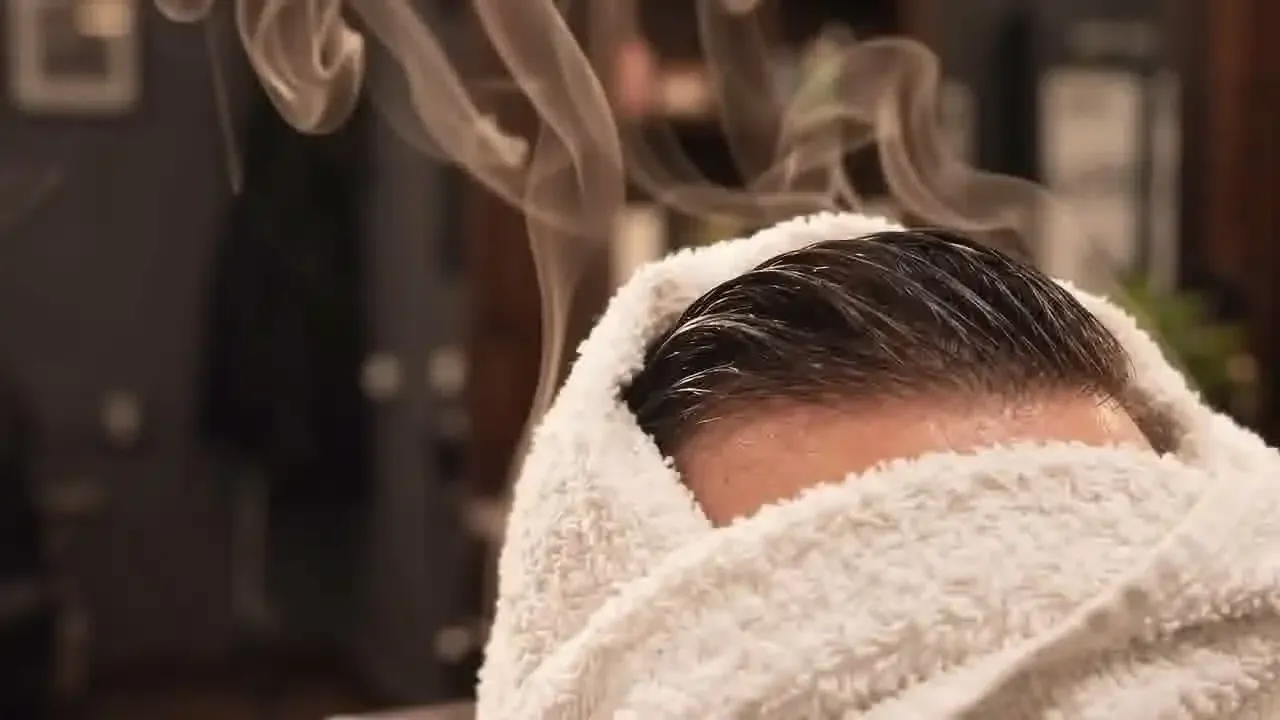 A client relaxing under a hot towel